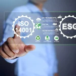 Visualisasi konsep Perubahan ISO 14001 versi terbaru yang menampilkan tampilan digital ISO 14001 terintegrasi dengan ESG (Environmental, Social, Governance), ikon keberlanjutan, pengurangan emisi CO2, dan simbol daur ulang yang disentuh oleh tangan profesional bisnis.