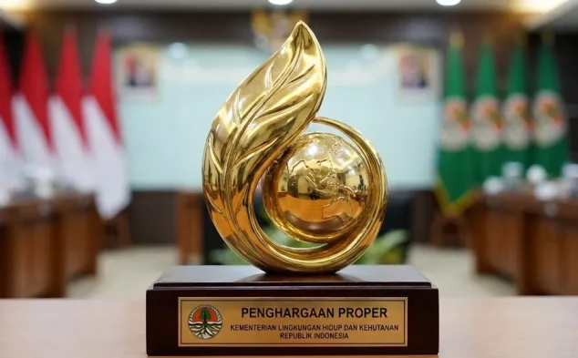 Trophy Penghargaan Proper berlapis emas dari Kementerian Lingkungan Hidup dan Kehutanan RI, menampilkan simbol daun dan bumi, dipamerkan di meja ruang rapat dengan deretan bendera Indonesia dan atribut lembaga di belakangnya—terkait implementasi standar lingkungan sesuai peraturan BPLH nomor 7 tahun 2025.
